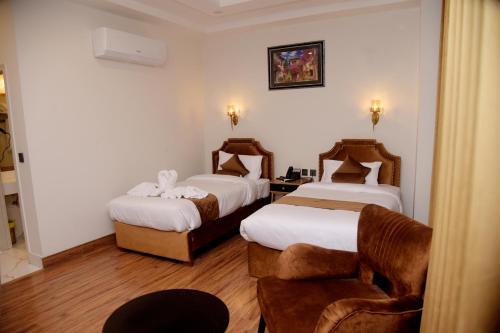 a hotel room with two beds and a chair at The Rich Hotel & Apartments in Lahore