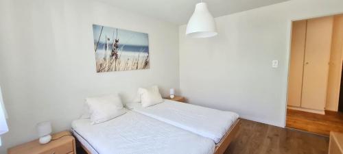 Un dormitorio con una cama blanca con una foto en la pared en Lorée 201 en Leukerbad