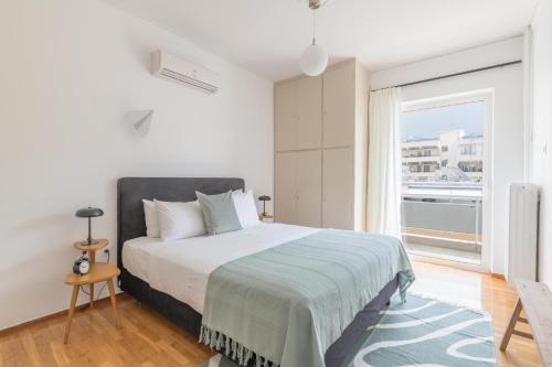 1 dormitorio con cama y ventana grande en Outstanding 2BR Apartment in Cholargos by UPSTREET en Athens