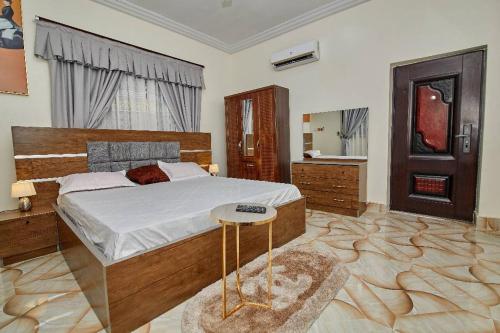 1 dormitorio con 1 cama grande y 1 mesa en Pomaa Villa, en Kumasi