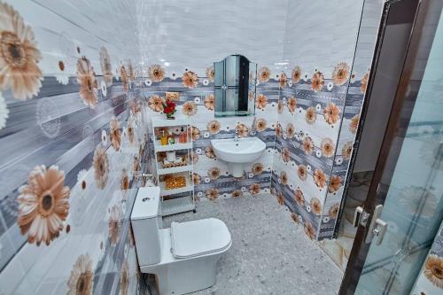 ein Badezimmer mit einem Waschbecken, einem WC und einer Wand in der Unterkunft Pomaa Villa in Kumasi