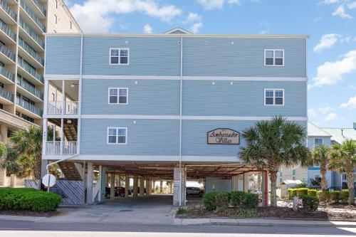a large blue building with palm trees in front of it at Spacious Penthouse Ocean Front 7 BR Condo - Ambassador Villas Unit 401 in Myrtle Beach