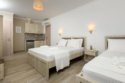 two beds in a bedroom with white walls and wooden floors at Aspa's House in Limenas