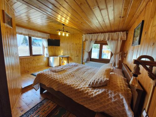 a bedroom with a bed in a wooden cabin at SEZATOAREA LUPILOR in Lepşa