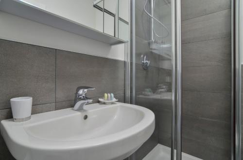 La salle de bains est pourvue d'un lavabo blanc et d'une douche. dans l'établissement Domino Apt, à Sarnico