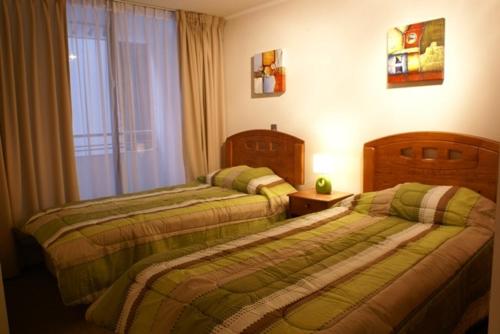 2 camas en una habitación de hotel con ventana en Apart Hotel Agustinas Plaza, en Santiago