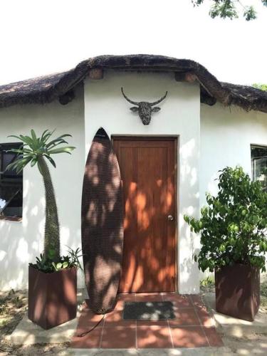 a house with a surfboard in front of a door at The Rondavel @ Foundation Lodge in Sodwana Bay