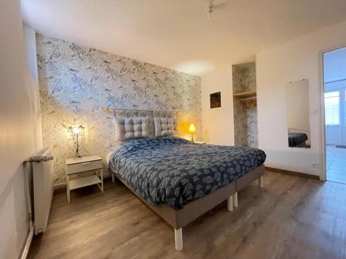1 dormitorio con cama y pared de piedra en Sérendipity, en Marquise
