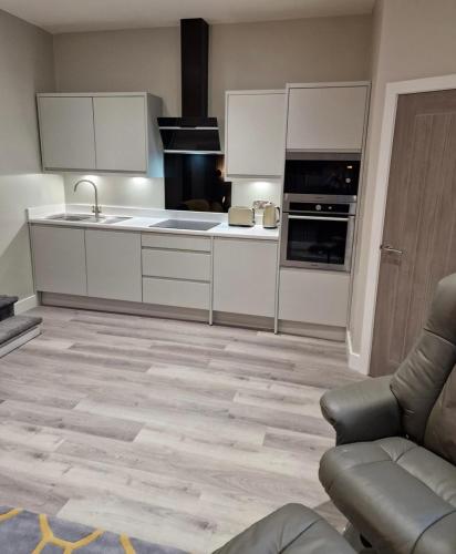 a kitchen with white cabinets and a couch in a room at Apartment in Uppermill in Saddleworth
