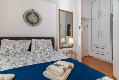 een slaapkamer met een bed met een blauwe deken en een spiegel bij Studio at Bacvice Beach in Split