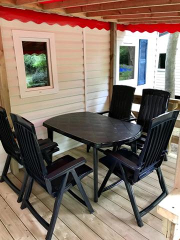 a black table and chairs on a porch at Camping de Pujol - Chalets - Argeles sur Mer - Lotus - 6P in Argelès-sur-Mer