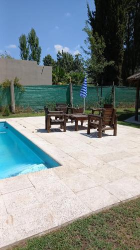 two wooden benches next to a swimming pool at ENTRE VIÑAS in Ciudad Lujan de Cuyo