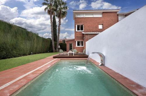 a swimming pool with a water fountain in a yard at Casa Sal y Sol junto a la playa cerca de Barcelona in Sant Vicenç de Montalt