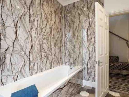 a bathroom with a white tub and a marble wall at Luxury 2 Bedroom Home in Leeds