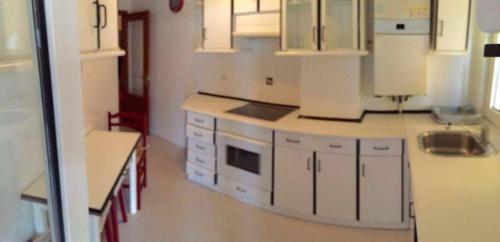 una cucina con armadietti bianchi ed elettrodomestici bianchi di Alojamientos Marte apartamentos a Torrelavega