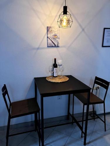 a black table with two chairs and a bottle of wine at Cozy flat in the heart of Buda in Budapest