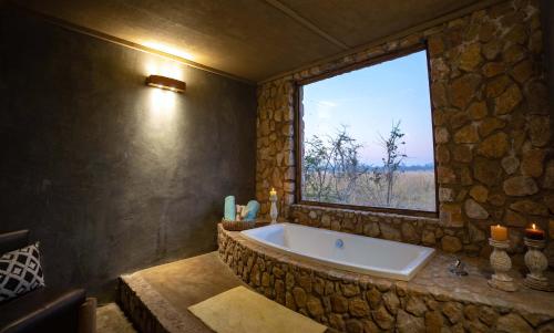 a large bath tub in a room with a window at Gwango Elephant Lodge in Dete