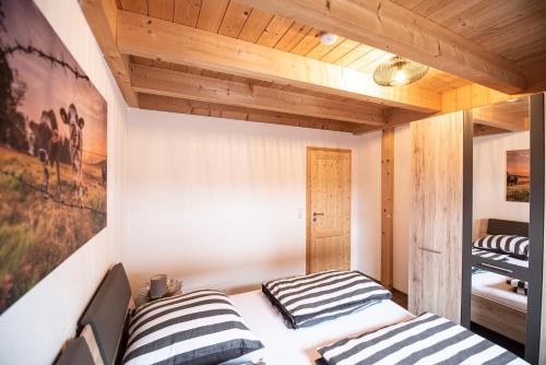 two beds in a room with wooden ceilings at Hirsch Chalet #Sauna in Lechbruck