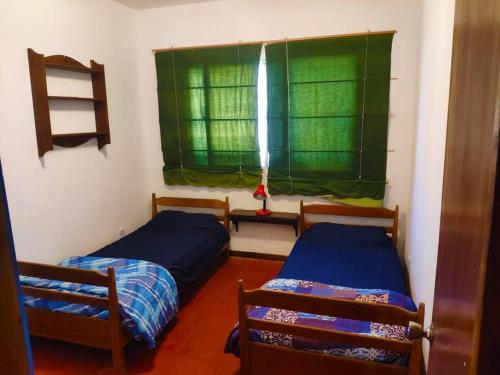 1 dormitorio con 2 camas y una ventana con cortinas verdes en Casa rural, en Nueva Palmira