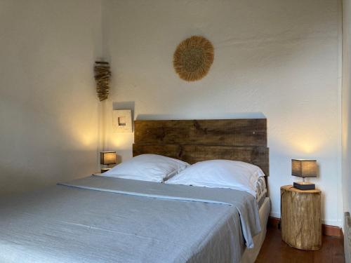 a bedroom with a bed with white sheets and two lamps at Casa a Stretta in Castello-di-Rostino
