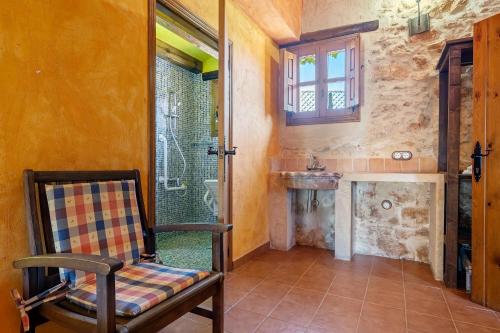 a room with a chair and a bathroom with a shower at Lo paller in Perelló