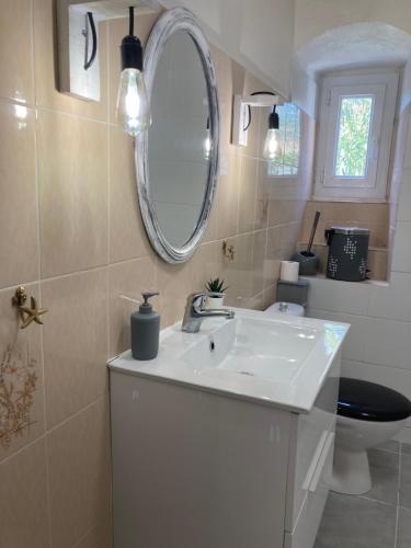 y baño con lavabo, espejo y aseo. en Casa a Stretta en Castello-di-Rostino