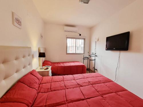 Lindo departamento en planta baja en Jujuy في سان سلفادور دي خوخوي: غرفة نوم بسرير احمر وتلفزيون بشاشة مسطحة