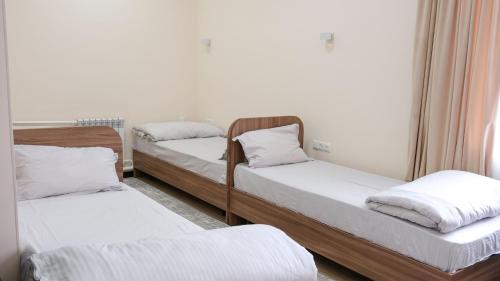 a room with three beds with white sheets at Apple Hostel Bishkek in Bishkek