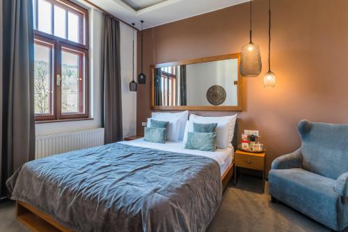 a bedroom with a bed and a blue chair at Wellness & spa hotel Augustiniánský dům in Luhačovice