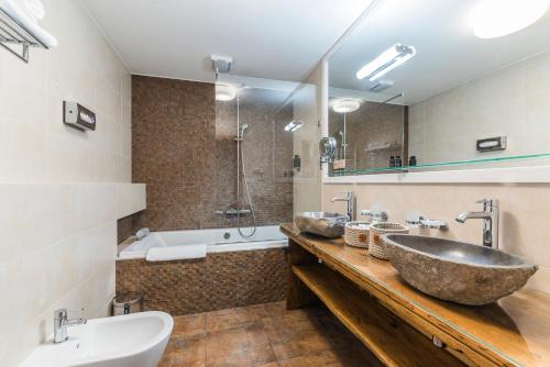 a bathroom with a large stone sink and a tub at Wellness & spa hotel Augustiniánský dům in Luhačovice