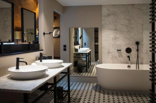 a bathroom with two sinks and a bath tub at Hôtel L'Incomparable Aix-Les-Bains in Tresserves