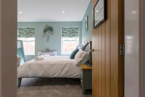a bedroom with a bed with blue walls and windows at Minerva House in Pocklington