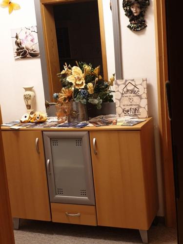 a cabinet with a television and flowers on it at Ferienwohnung Haus Veronika in Wegscheid