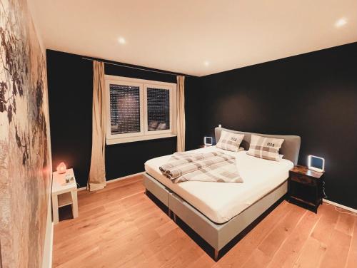a bedroom with a large bed with a black wall at Starnberger See in Feldafing