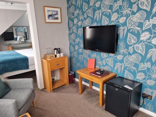 a hotel room with a bed and a tv on the wall at Brookside Guest House & Mini Spa in Brixham