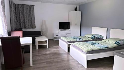 una camera con due letti, un tavolo e un divano di Aparthotel DKS a Chomutov