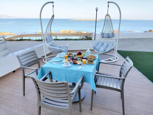 Klinakis Beach Hotel في مدينة خانيا: طاولة زرقاء مع كراسي والطعام على شرفة