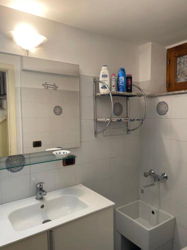 a white bathroom with a sink and a mirror at Majolica Taormina Apartment in Taormina