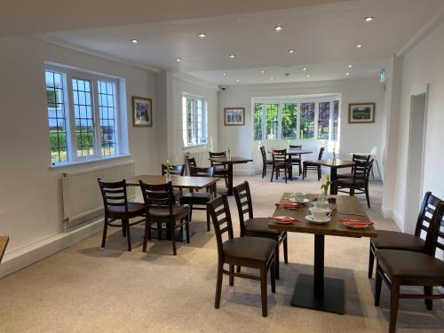 a dining room with tables and chairs and windows at Old Farm Hotel in Birmingham