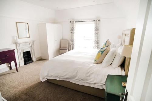 a white bedroom with a bed and a window at Woodyear House - Cowes - Sleeps 8 - 4 Bed - Dog Friendly - Waterfront in Cowes