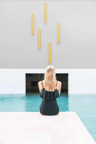 a woman sitting on the edge of a swimming pool at Kurhotel Skodsborg in Skodsborg