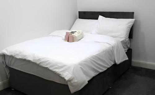 un letto con lenzuola bianche e una scatola sopra di Contemporary Comfort - Central Bradford Flat a Bradford