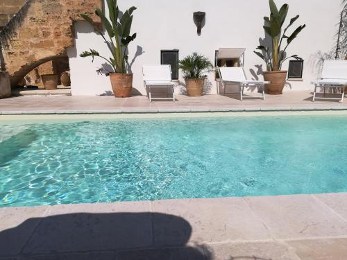 a swimming pool in a yard with chairs and a house at Dimora Maltese in Morciano di Leuca