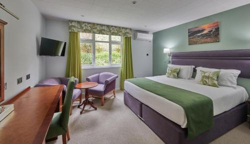 Habitación de hotel con cama, escritorio y mesa. en Best Western Moores Central Hotel en St. Peter Port