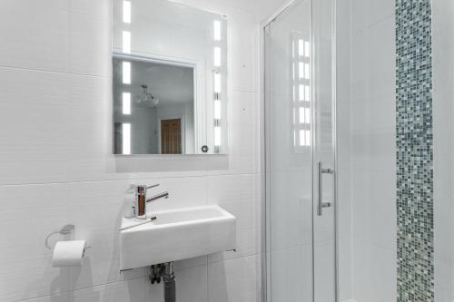 a white bathroom with a sink and a mirror at 3 At The Beach, Torcross in Beesands