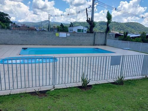 a white fence around a swimming pool in a yard at Apartamento inteiro com garagem coberta Treviso in União da Vitória