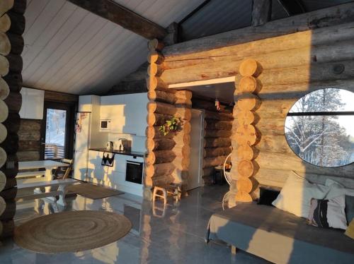 a kitchen and living room with a log wall at Upea kelohirsihuvila rannalla, myös poreamme! in Joensuu