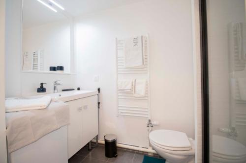 a white bathroom with a toilet and a shower at RESIDENCE SEVIGNE A Disneyland in Coupvray