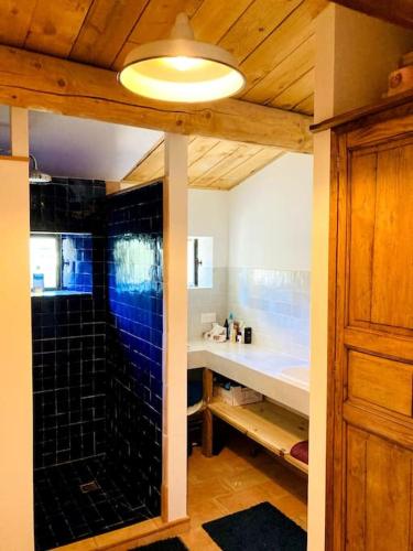La salle de bains est pourvue d'une douche et d'un mur carrelé bleu. dans l'établissement Maison à Aix en provence au pied de la Sainte Victoire, à Beaurecueil