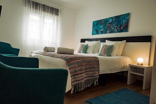 a bedroom with a large bed with a blue painting at Breathe In in Zambujeira do Mar